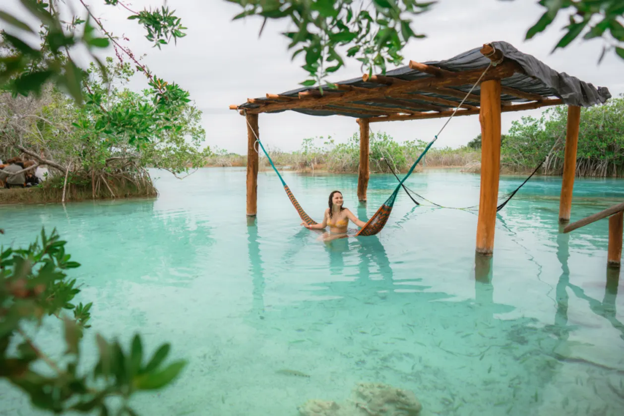 Winter travel inspo: woman resting in hammock in water in Bacalar Lagoon in Mexico